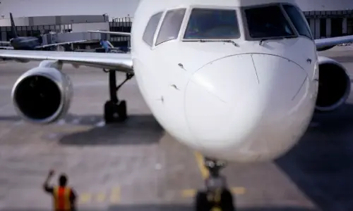 A depth of field shot of an airplane at a terminal being boarded by passengers.