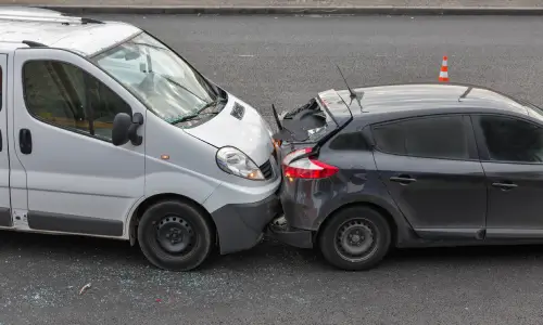 A rear-end accident between a white delivery van and a grey hatchback.