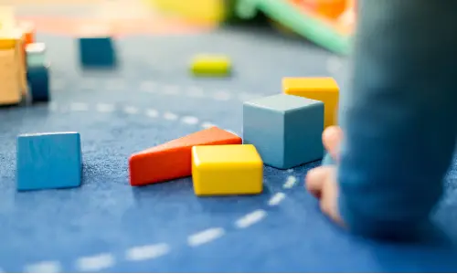A depth of focus shot of a toddler playing with blocks at a daycare.