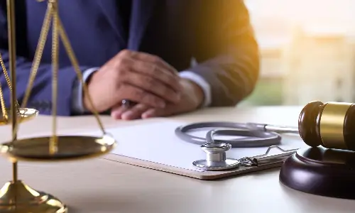 A medical malpractice lawyer seated behind his desk with scales and a gavel.