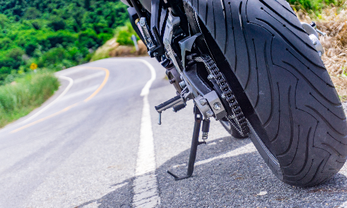 A closeup of a motorcycle's tyres as it drives on a hillside road.