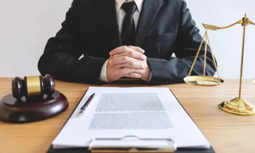 A car accident lawyer reviewing a client's insurance contract from behind a desk.