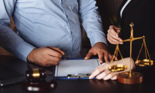 A personal injury lawyer and a client at a table reviewing the terms of an insurance agreement.