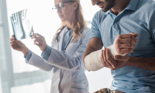 A doctor viewing X-rays of a patient who was injured in an accident and wears a cast.