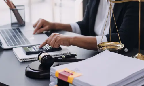 A personal injury lawyer seated at a desk and calculating damages a client can receive.