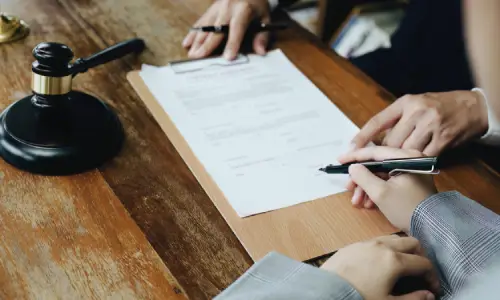 A personal injury lawyer pointing out where on a form her client should sign.