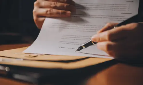 A closeup of a lawyer's hand as they explain details of an insurance claim.
