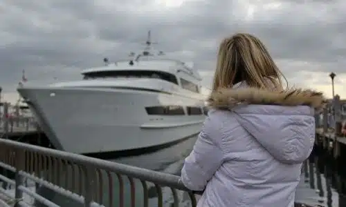 A woman at a dock waiting to board a ferry.