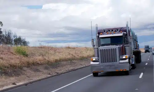 Large tractor trailer trucks driving on a highway on a cloudy afternoon.