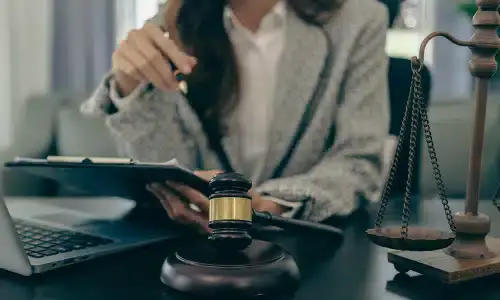 A lawyer in her office holding a clipboard with documents for a client's claim.