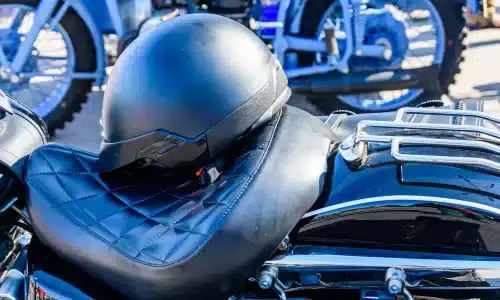 A black helmet placed on a motorcycle's leather seat on a sunny day.