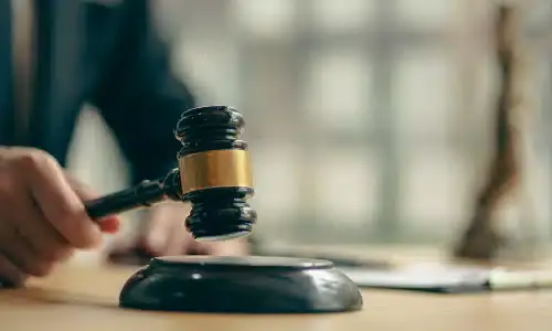 A selective focus shot of a lawyer holding a gavel while seated at his desk.