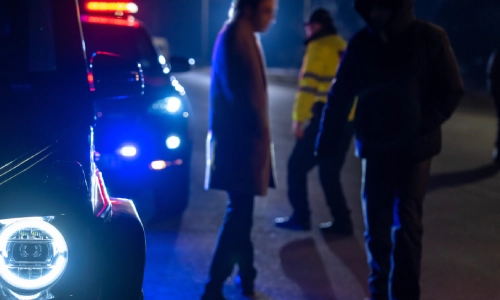 Police officers interviewing a party involved in a car accident at night.