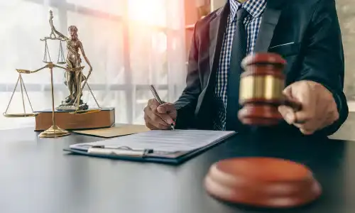 A personal injury lawyer in an office holding up a gavel over its soundblock.