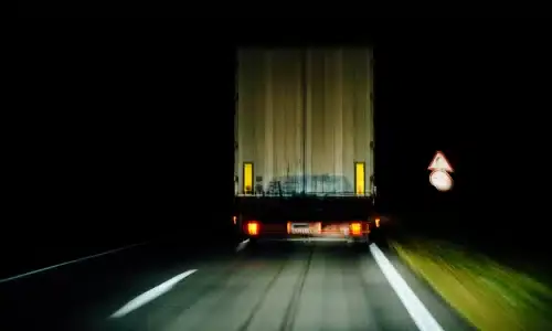 A shot of the rear of a large semi truck driving on a highway at night.
