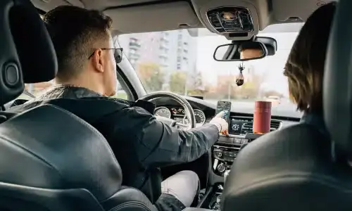 A rideshare driver adjusting his app as he's about to drive a passenger.
