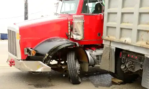 A red semi truck pressed against the rear of a dump truck it collided with.