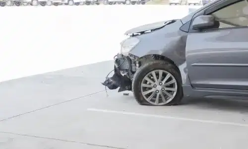 A grey car with an exposed engine block after a hit and run accident.