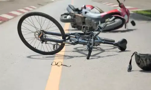 A bicycle and a motor scooter lying on a road after a collision between the two.