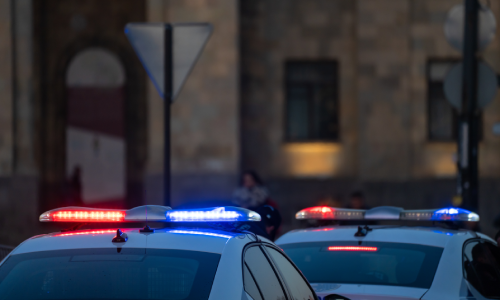 Police cars displaying their flashers on top of their roofs in the evening.