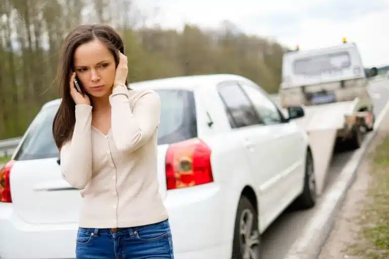 A woman calls for help as a car is being taken away on a tow truck.