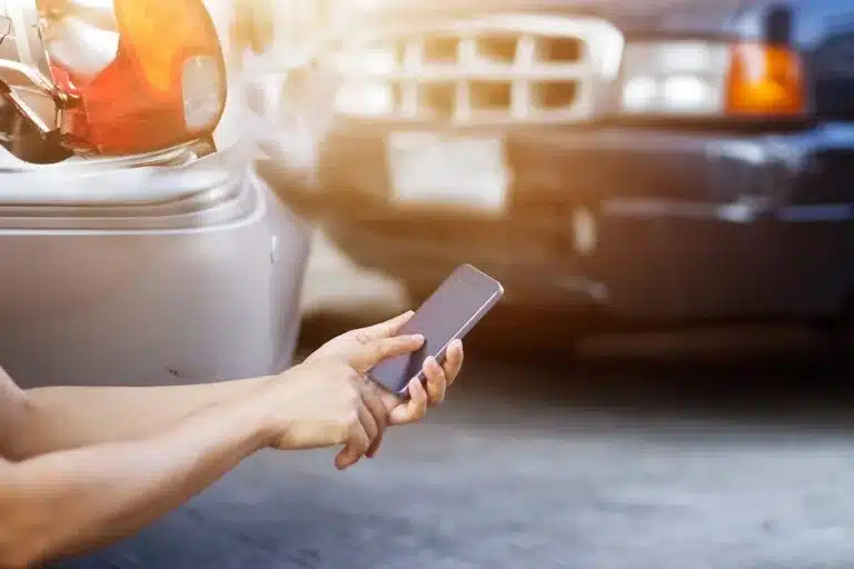 A man searches for answers on his cell phone after a car accident without insurance.