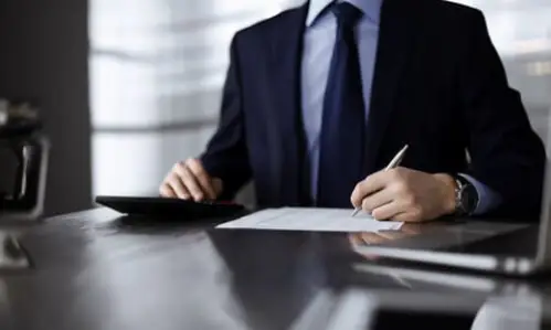 A slip and fall accident lawyer calculating damages for his client while at a desk.