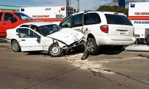 Two white vehicles in the middle of an intersection after an accident.