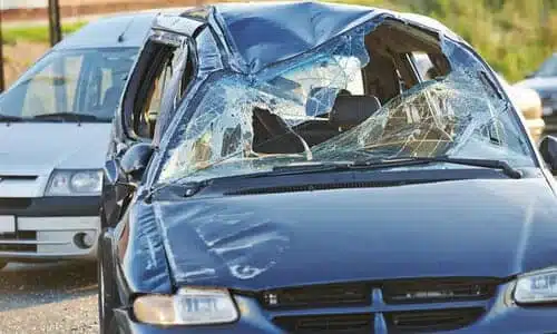 A totaled drunk driver's black sedan after an accident with a white van.