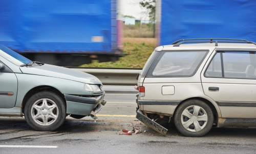 Two cars stopped on a road after a rear-end collision between the two.
