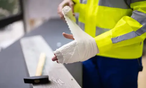 A worker bandaging his hand after sustaining a workplace injury.