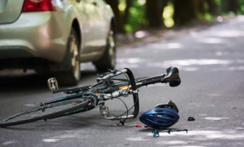 A bicycle tipped over next to a car that collided with it.