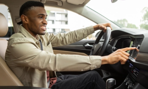 A rideshare driver smiling and adjusting his GPS device.