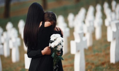 Two women embracing each other at the grave of a wrongful death victim.