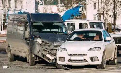 A van and a car in the middle of the road after colliding with each other.