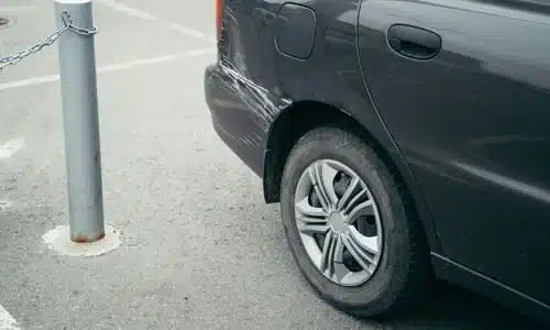 A damaged car in a parking lot after another driver scratched it and left the scene.