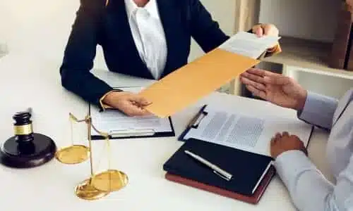 A defective products lawyer pulling out files from an envelope to present to a client.