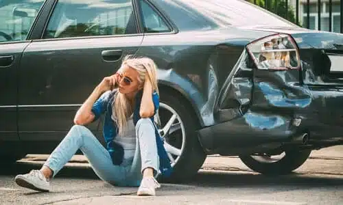 A woman calling for help after a hit and run accident damaged her black car.