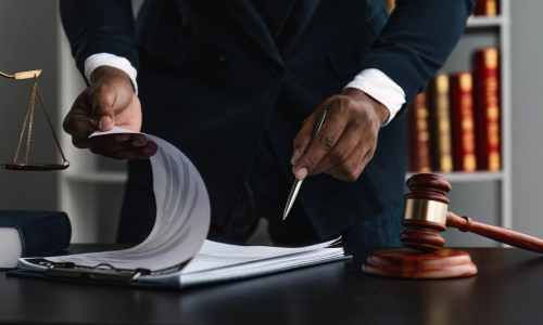 A personal injury lawyer holding a pen and reviewing forms his client filled out.