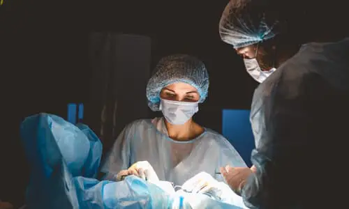 A team of doctors performing invasive surgery on a patient in an operating theater.