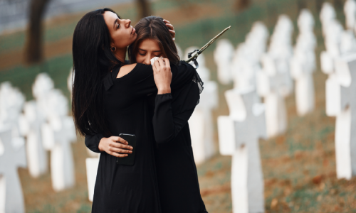 Two mourning women in a graveyard after the funeral of a wrongful death victim.