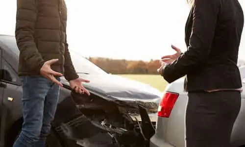 A man and a woman arguing over a rear-ender accident on the road.