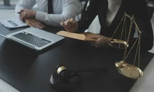A pair of workers' compensation lawyers about to hand an envelope containing compensation to her client.