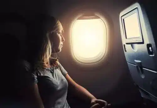 A woman looks out of the window of a commerical airline.