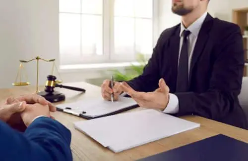 A distracted driving accident lawyer talks with a client about a case in a modern office.