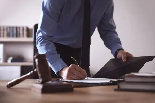 A Duluth rideshare lawyer takes quick notes while standing at his office desk.