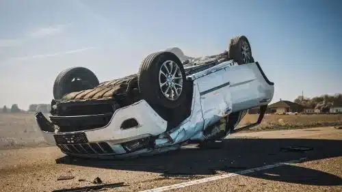 A crashed white car is on its roof after a drunk driving accident.