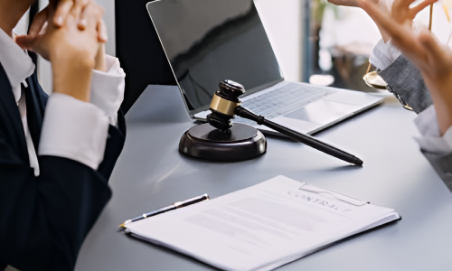 Two San Diego personal injury lawyers discussing the details of a case over a desk with an opened laptop and gavel. 