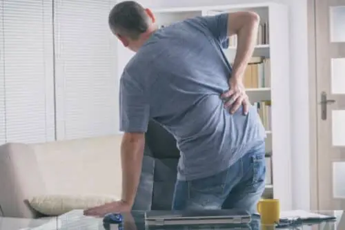 An injured man holds his back with a spinal injury.