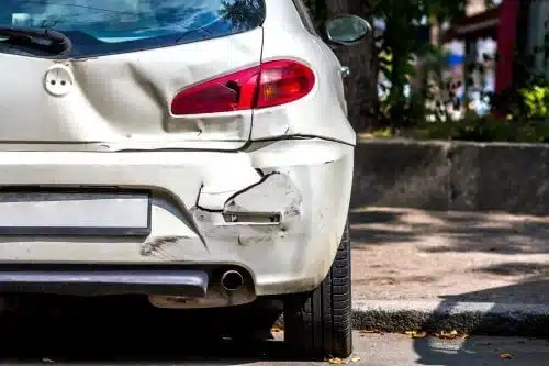 A small white car with rear end damage.